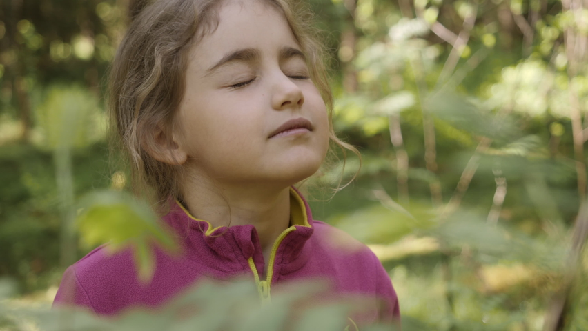 Portrait Child Girl Exhaling Fresh Air, Taking Deep Breath, Reducing Stress in Forest. Dreamy Peaceful Relaxed Smiling Kid Girl Breathing Fresh Air Nature, Tranquil Caucasian Child Alone Outdoors. Royalty-Free Stock Footage #1077530213