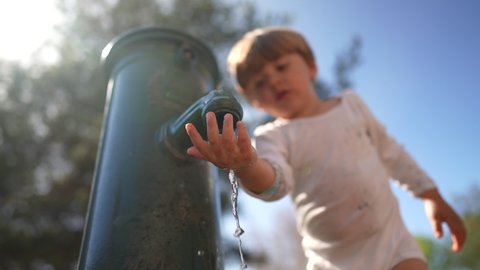 Children drinking from water faucet at park in slow-motion