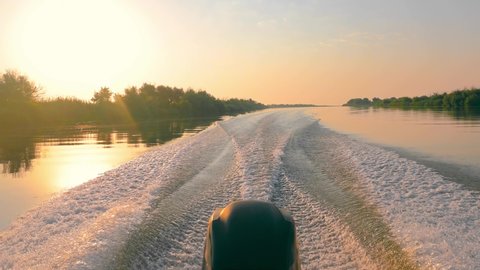 View from a motor boat moving at sunrise in the Danube riverbed. Speed boat and motor running at high speed. Beautiful view and sunrise from a motor boat