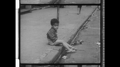 1950s New York City, Young Puerto Rican Kid or Black Child sitting on  City Street. The city gutter is littered with trash. 4K Overscan of Vintage Archival 16mm Film Print