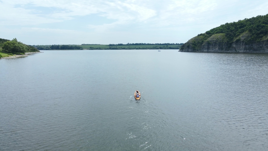 A man with a dog happy together in a canoe floats on the river in the highlands