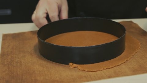 the hands of a pastry chef man made a circle out of the dough using a metal mold and removed the excess dough. On a silicone mat