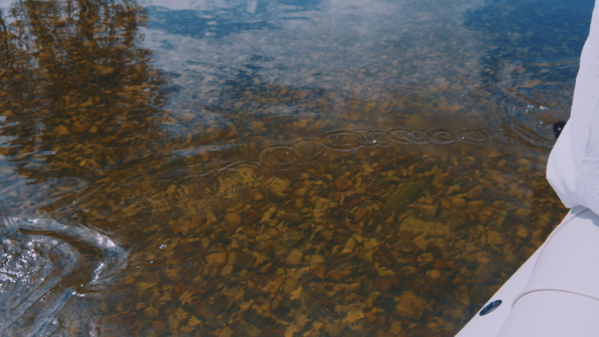 Person sits on the raft and paddles on the shallow river