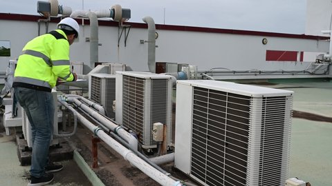 Air conditioning technicians repair and maintain condensing units outside the building, engineers inspect the operation of ventilation fans.
