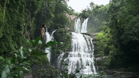 Man gazes at Nauyaca waterfalls Costa Rica rain forest, slow motion