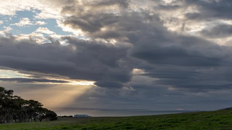 Sunrays burst from a cloudy sky and illuminate the ocean in time lapse from Kangaroo Island (South Australia)