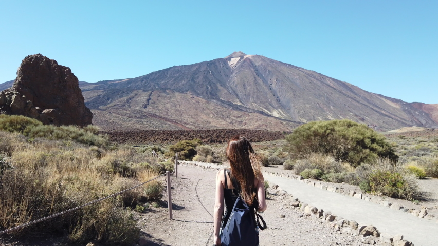 Tracking shot of woman with the background of the volcano Teide in the background.