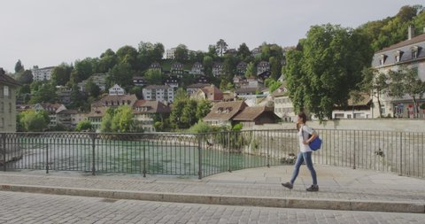 Woman walking in Bern, Switzerland. Woman visiting tourists attractions and landmarks in Berne. Mixed race Asian Caucasian girl on the Nydegg Bridge by the Aare river