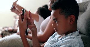 Hispanic young boy using cellphone device. Candid kid playing game on smartphone device