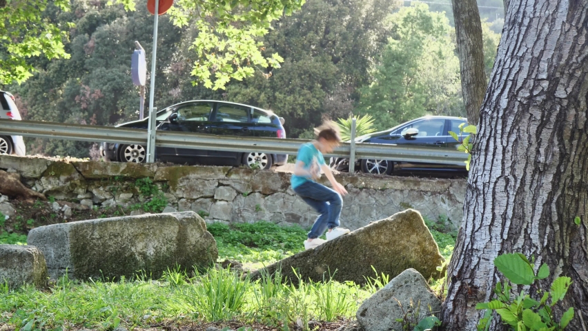 boy jumps on a stone in the park