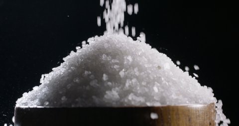 White table salt granules falling on wooden surface and forming a pile. Condiment particles dropping. Clean cosmetic bath salt 4k footage