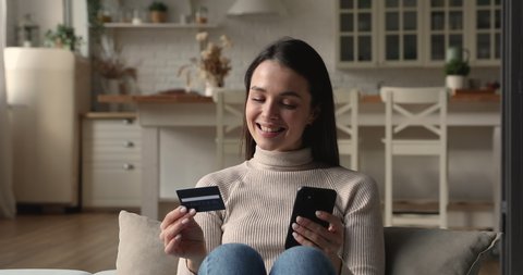 Happy focused young woman entering payment information form plastic card in cellphone application, shopping in internet store, purchasing goods or paying for services online, ecommerce concept.