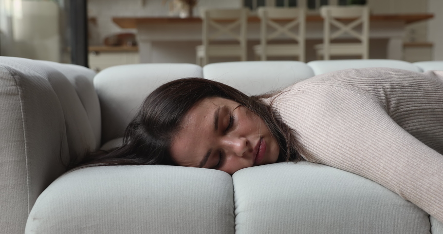 Exhausted young woman fallen asleep on comfortable sofa, feeling no energy after hard working day. Tired millennial female flopped down on cozy couch, needs rest at home, chronic fatigue concept. | Shutterstock HD Video #1077576746