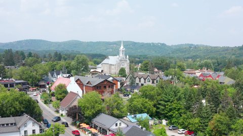 Aerial Drone Establishing Shot of Saint-Sauveur, Quebec During Busy Summer Months. Church Located on Rue Principale.