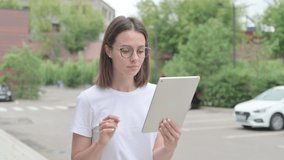 Young Woman making Video Call on Tablet while Walking on Street 