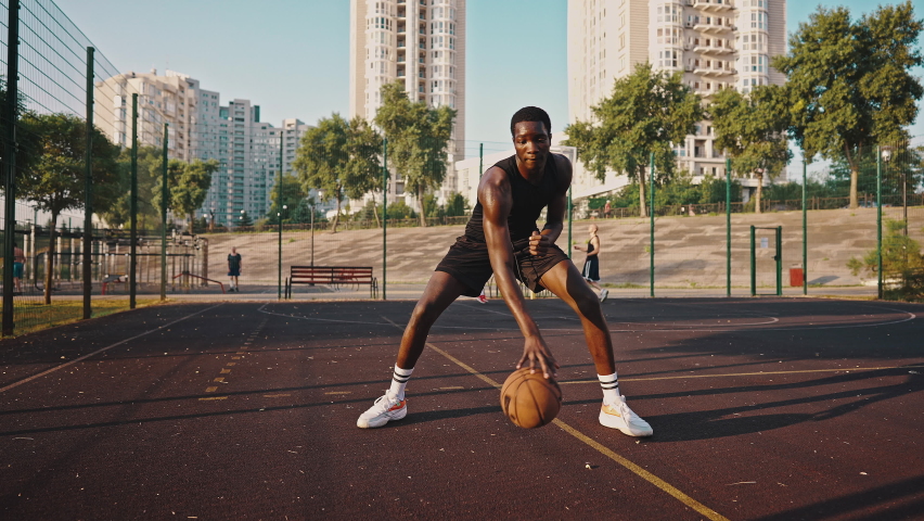 Close-up of a young black basketball player dribbling the ball across the field. Male athlete training on the basketball court. Royalty-Free Stock Footage #1077580883