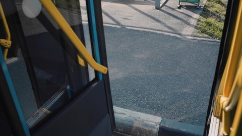 The doors of the passenger bus open at the bus stop. Shooting from inside the bus