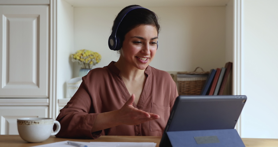 Happy young Indian woman in headphones start videoconference on digital tablet by business or study sit in homeoffice room. Video call event, apps, on-line tutor start virtual meeting class concept Royalty-Free Stock Footage #1077583892