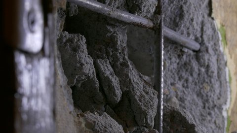 Ungraded: Worker hollows out a hole in reinforced concrete wall with hammer and chisel. Ungraded H.264 from camera without re-encoding.