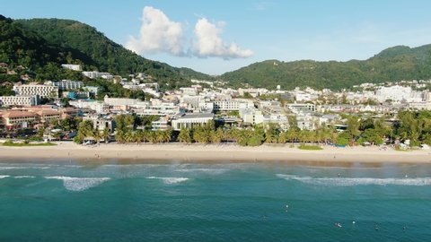 Beautiful Drone shots sea and sand on summer day.Top view popular beach famous tourist Patong city in Phuket,Thailand.waves breaking to sand for long beach outdoor.Beautiful sunset over mountains.
