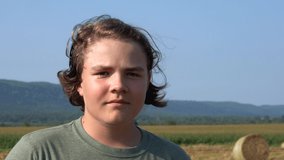 A video portrait of a teenaged boy in a farm field.