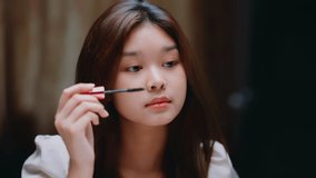 Young  Asian beautiful woman and professional beauty make up artist vlogger recording makeup tutorial in beauty studio to share on the website or social media. Blogger use mobile on a tripod and ring 
