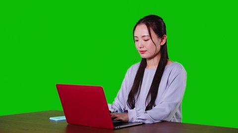 Young asian woman using a laptop PC. Green background for chroma key composition.