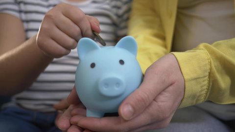 Family piggy bank for investment. Happy family throws coins into piggy bank. The girl hand throws coins into piggy bank. Family business. Mom and daughter are counting coins. Girl with piggy bank