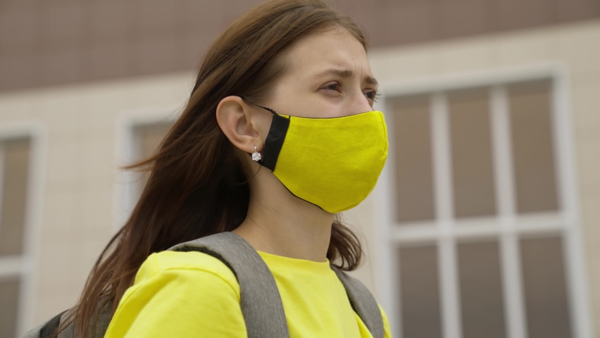 Schoolgirl girl in a mask with a backpack talks on a smartphone online, modern trends in technological progress, protect herself from coronavirus infection, air filtration Royalty-Free Stock Footage #1077608030