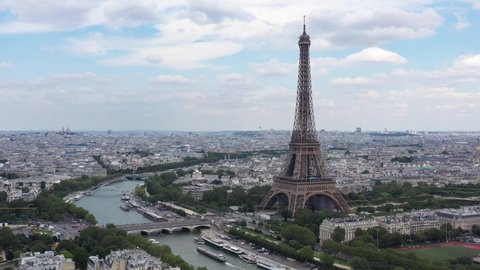 France, Paris Tour Eiffel (Eiffel Tower), cloudy summer day, with Champs-de-Mars garden and Iena bridge. Long drone shot, aerial view above Seine river