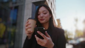 Joyful young asian business girl using mobile phone networking with online friends typing messages drinking coffee outside. Beautiful people. City life. - Powered by Shutterstock - Get 15% off with code: PIKWIZARD15