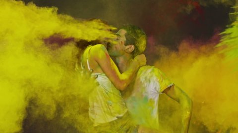Young romantic couple kissing and hugging each other . Beautiful young people having fun and splashing colorful holi . Holi festival background . Slow Motion shot on RED EPIC Cinema Camera 300fps