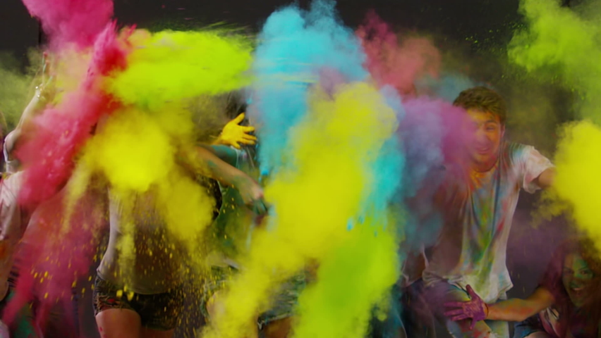 Beautiful young people having fun and splashing colorful holi . Holi festival of colorful kicks . Different colored powder explosions from hand . Slow Motion. Shot on RED EPIC Cinema Camera 300 fps Royalty-Free Stock Footage #1077620843