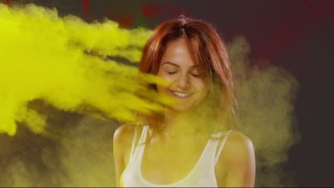 Yellow colored holi kick to the woman's face . Beautiful young people having fun and splashing colorful holi . Holi festival . Slow Motion shot on RED EPIC Cinema Camera 300fps