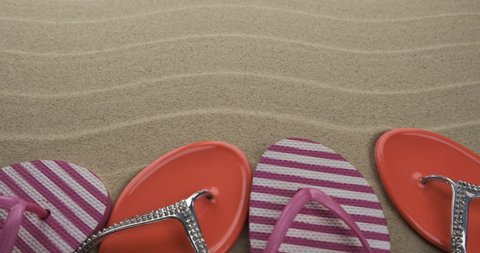 Fashionable flip flops standing on the beach sand. Slider shot. Top view. With space for design, text place.