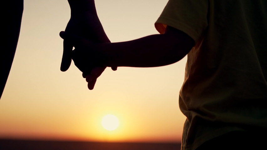 Happy family mom and daughter. Holding hands together. Happy family in park at sunset. Mom holds her daughter hands. Hands at sunset. Happy family concept. Hands of mom and daughter at sunset. | Shutterstock HD Video #1077625313
