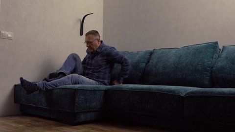 Middle-aged man relaxing reading a book at night on a sofa