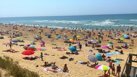 Lit-et-Mixe, France - August 2021 : Cap de l'Homy beach full of people sunbathing on their towels and resting under theirs parasols in Lit et Mixe, France during a heat wave