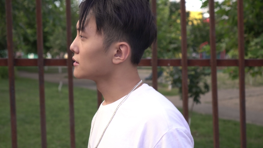 Portrait of a young Asian man outdoors. Korean male teenager walking down the street