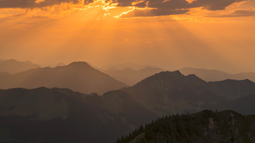 Timelapse of sun rays emerging though the dark storm clouds in the mountains. Sunset bavaria pre alps mountains germany europe forest.