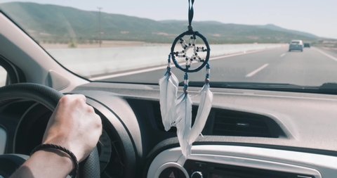 Driving car on highway with dreamcatcher hanging on rearview mirror, pov shot.