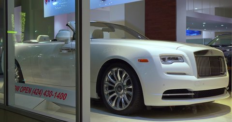 LOS ANGELES, CALIFORNIA, USA - AUGUST 7, 2021: Rolls-Royce luxury car dealership display showroom during sales event at night in Los Angeles, California, 4K