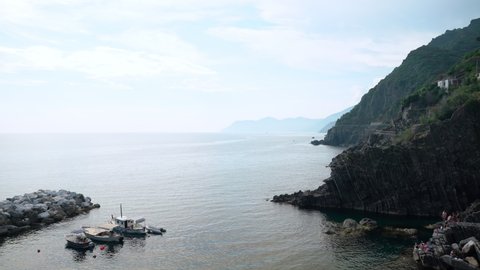 Riomaggiore, Italy - June 11. 2021: View of Mediterranean Sea, panning to Riomaggiore, town in Cinque Terre in Italy