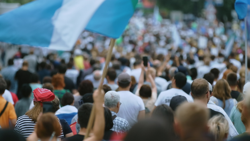 Protest people crowd on political riot in Russia marching on city streets, peaceful non-violent demonstration rally. Crowded protesters march with banners, placards, posters and signs on picket strike Royalty-Free Stock Footage #1077653672