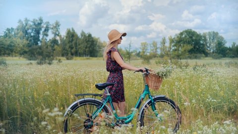 Cyclist Lady Moving On Bike On Countryside.Woman Cyclist Riding On Bicycle In City Park.Woman In Hat Enjoying Summer.Happy Beautiful Girl Cycling With Bike.Girl Cycling On Bike With Basket At Vacation