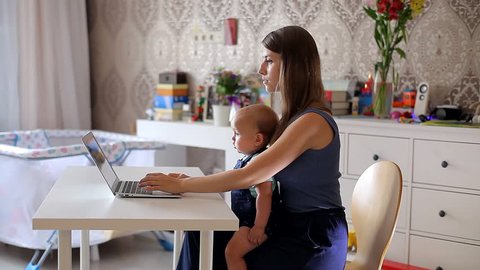 Young Mother with a Child Working at a Computer