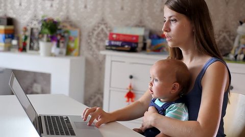 Young Mother with a Child Working at a Computer