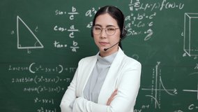 Young asian teacher woman teaching standing with arms crossed video conference with student. Female teacher training the mathematics in classroom blackboard from online course.