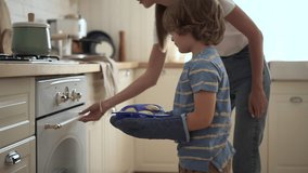 Young mother, son putting baked goods in oven and standing in home kitchen. - Powered by Shutterstock - Get 15% off with code: PIKWIZARD15