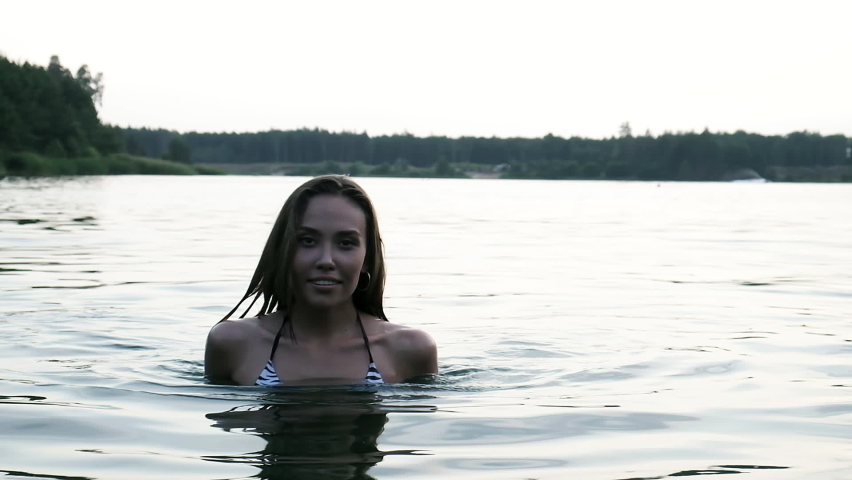 slim wet pretty female in bikini walking out of water after swimming in lake. fit asian woman in swimwear go out of river to beach in slow motion. summer chill, vacation, rest and pleasure at nature